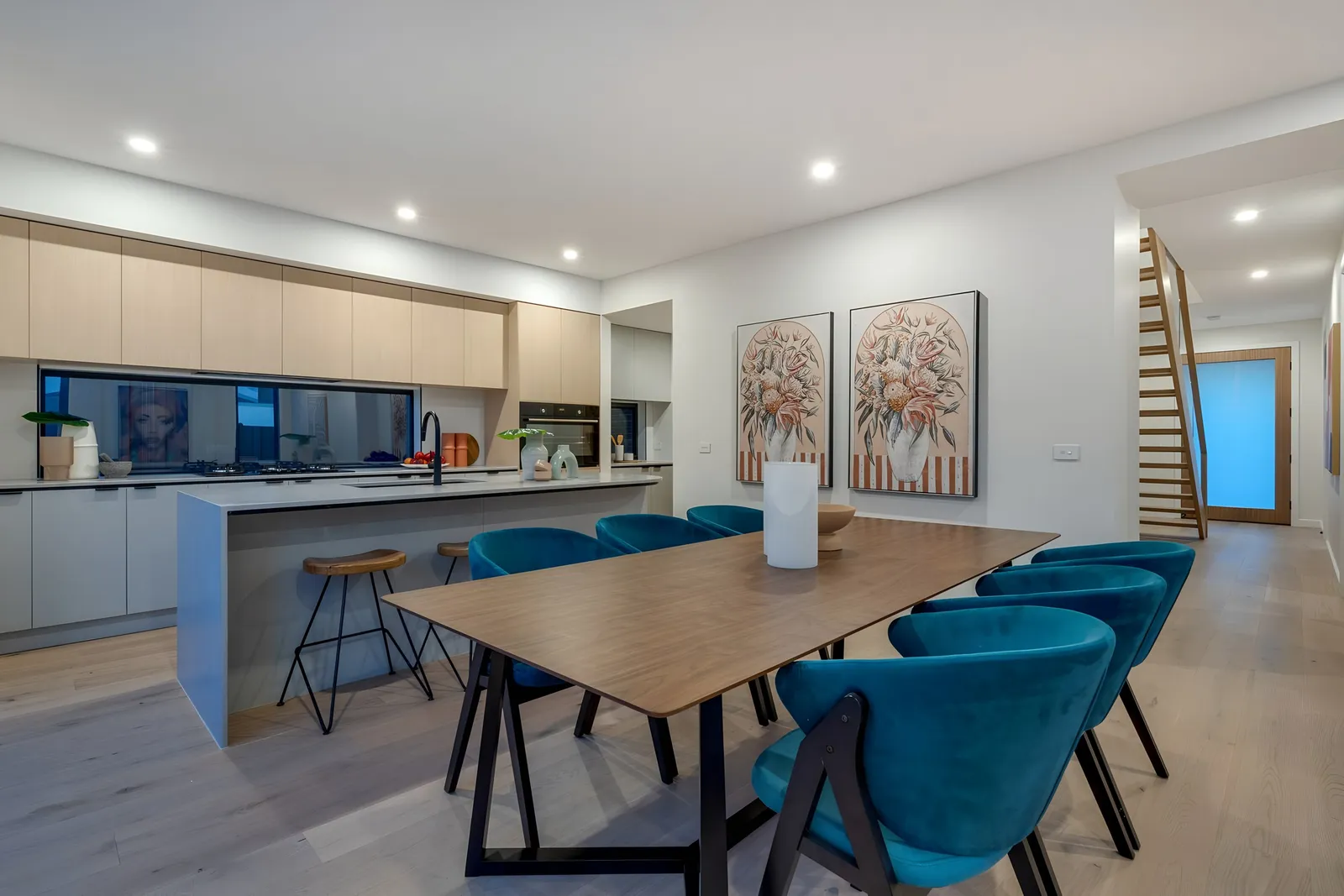 Open-plan kitchen and dining with a stone island and teal dining chairs